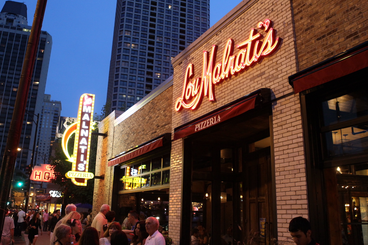 The exterior of a Lou Malnati's storefront shown at dusk.