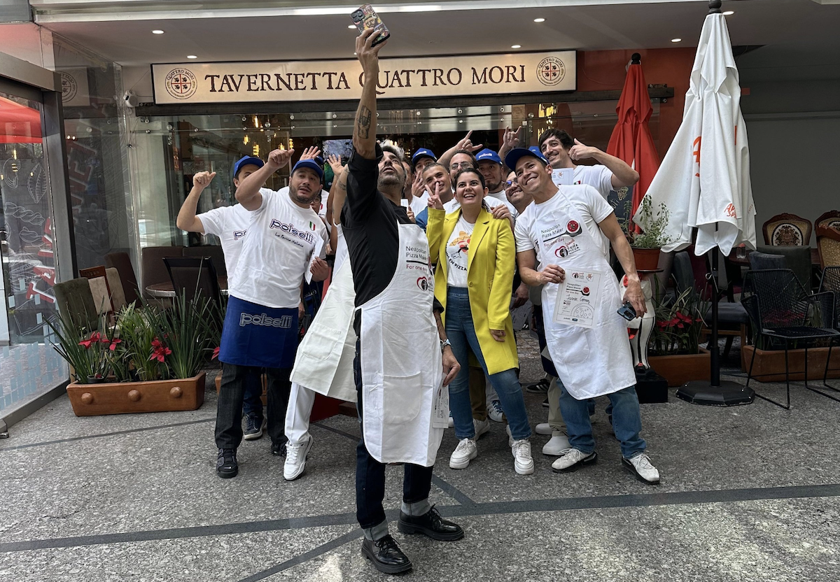 A group of about 15 pizza makers pose for a selfie on the streets of Mexico City.