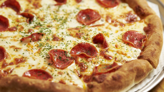 This photo shows a close-up of a beautiful pizza topped with melty cheese and ham.