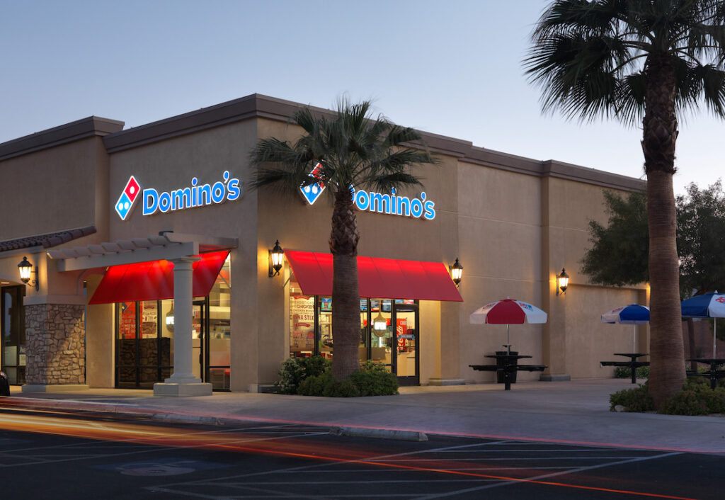 This photo shows the exterior of a Domino's restaurant in Las Vegas with a tall palm tree in front.