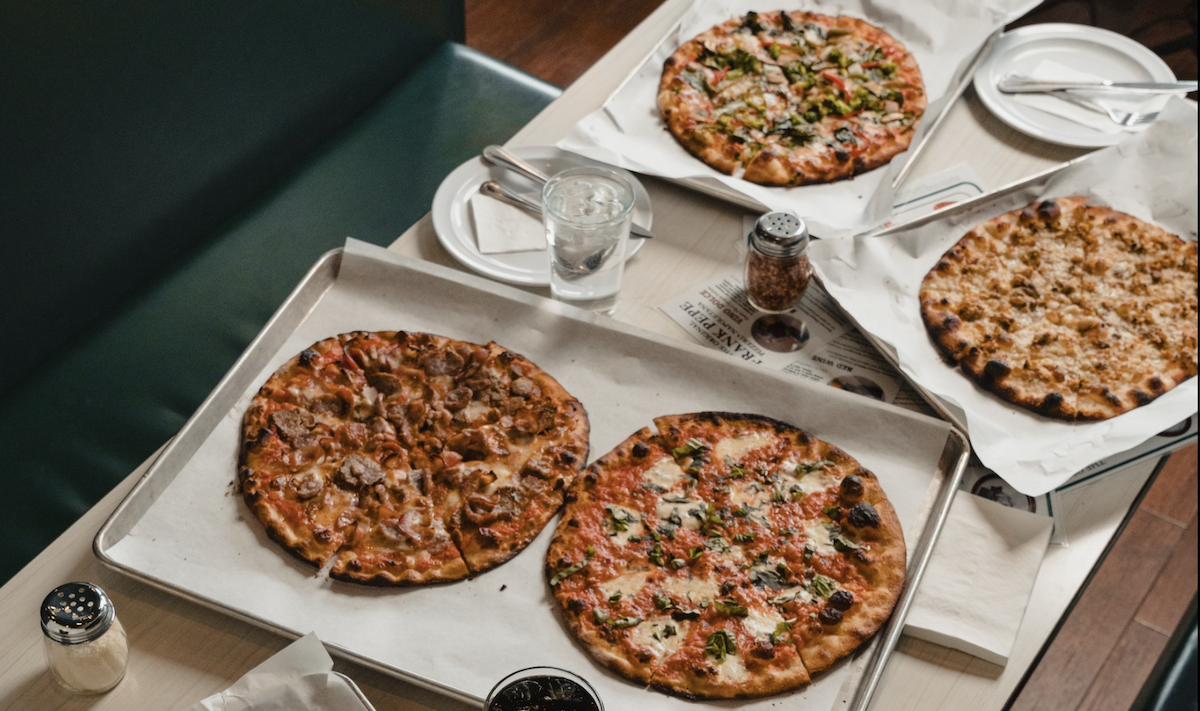 A spread of four different New Haven Style Pizzas sit on a table.