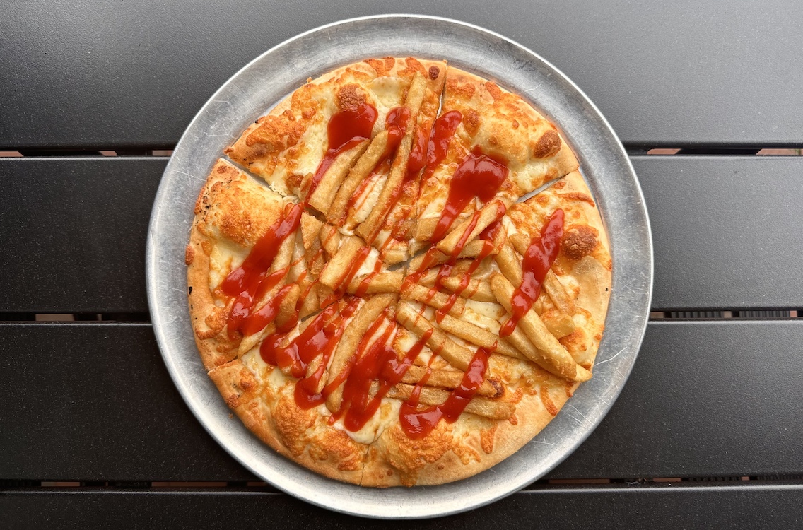 This photo shows a pizza topped with French fries.