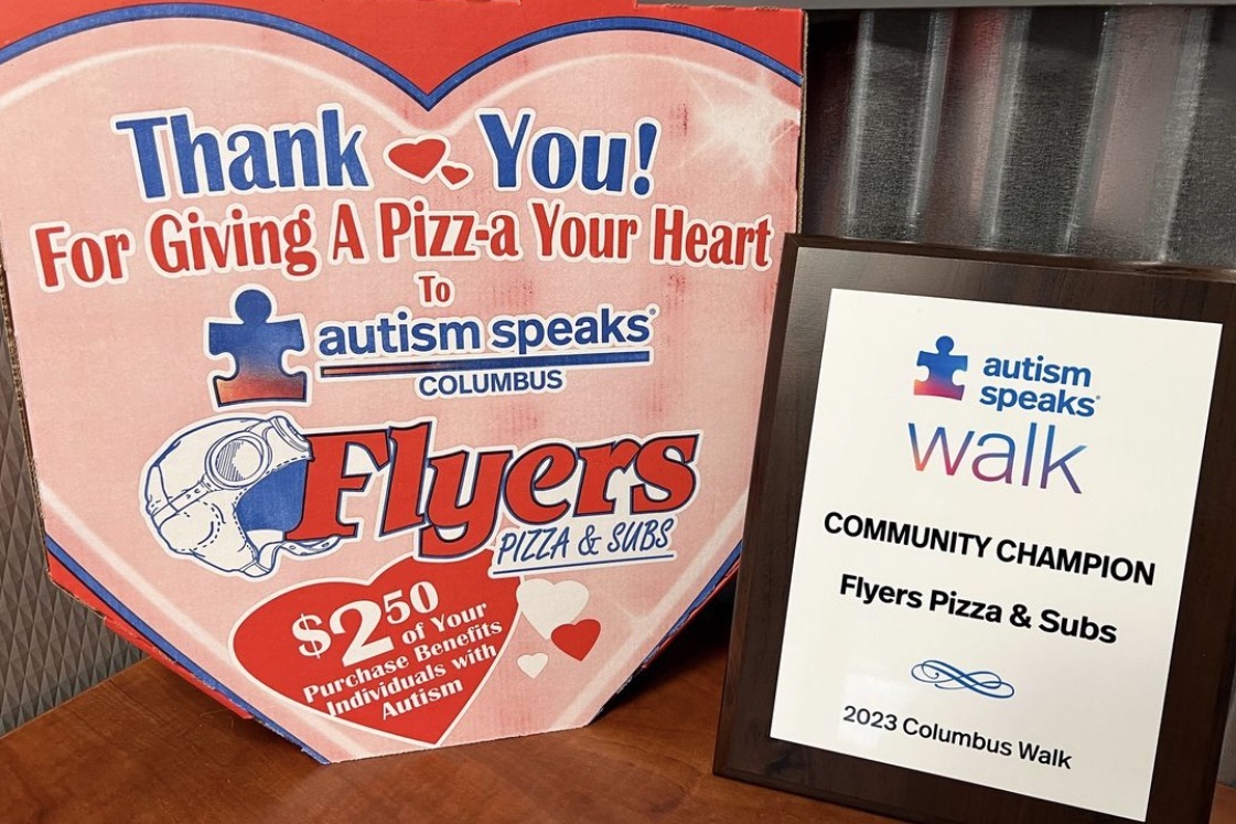 This photo shows a custom-made pizza box that says, Thank You! Giving a Pizza-a Your Heart" and has the Autism Speaks and Flyers logo.