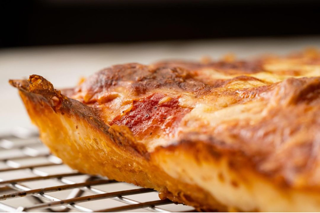 This photo shows the crispy frico edge of a pizza slice from Pizza Freak Co.