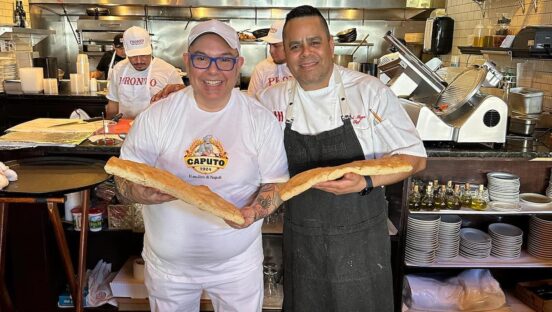 This photo shows Leo and one of his students holding a pair of rectangular pizza crusts in a pizza shop.