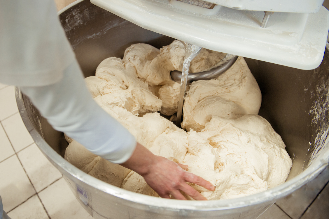 This photo shows a baker preparing dough in a dough mixer.