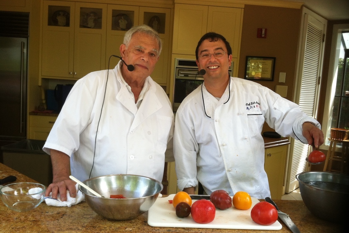 This photo shows a father and son, Larry and Richard Aronson, wearing white chef coats and using a variety of tomatoes to make sauce.