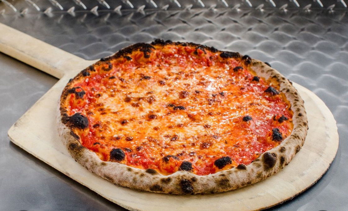 This photo shows a New Haven-style pizza with a nicely blistered crust on a pizza peel.