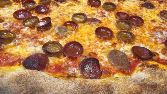 This photo shows a close-up of a pizza with cup-and-char pepperoni and a mozzarella and cheddar blend.