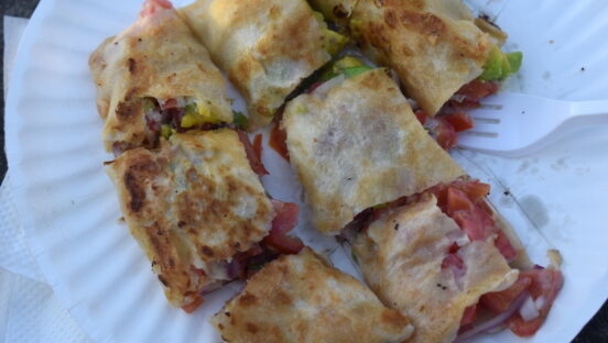 This photo shows a vegetable filled Zanzibar "pizza" cut into thick slices with golden brown dough.