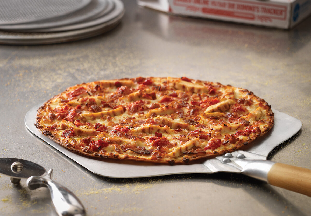 A Domino's Crunchy Thin Crust pizza on a peel.