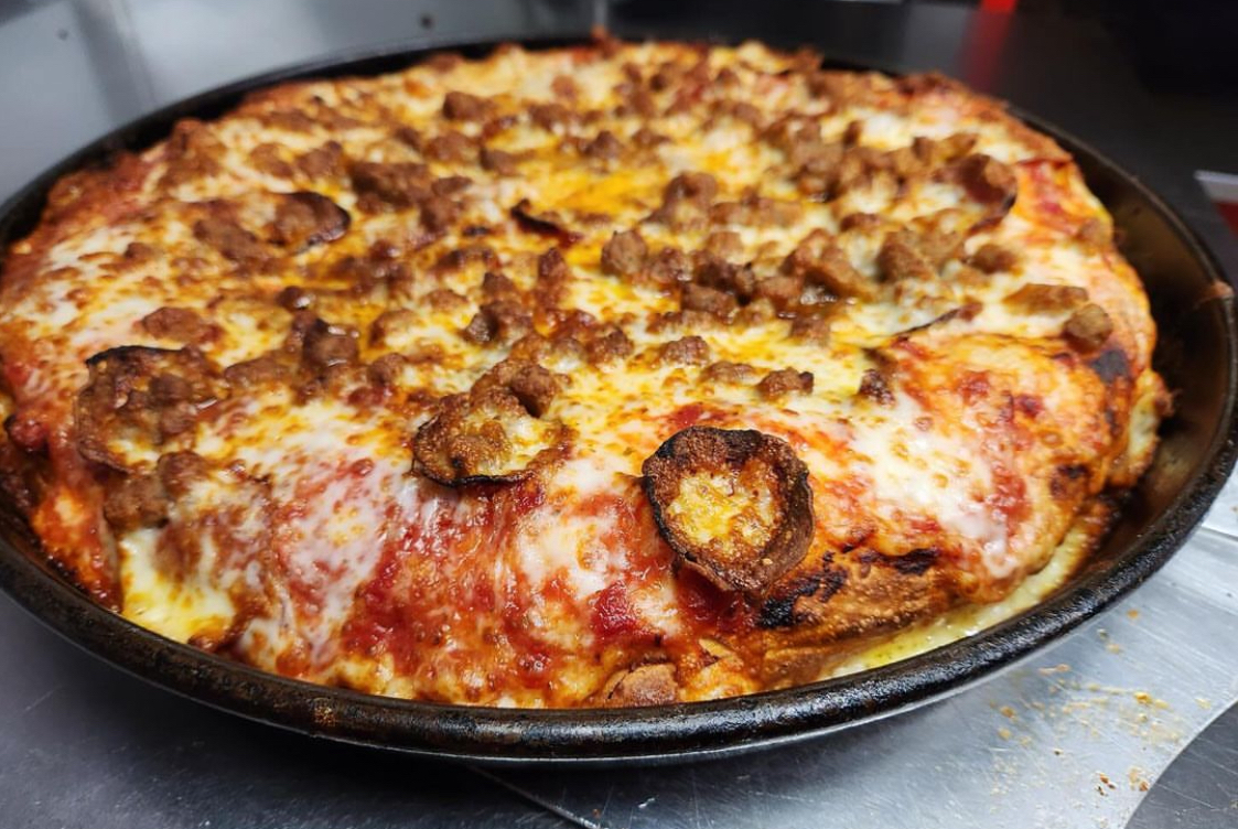 This photo shows a deep-dish pizza with cupped pepperoni, sausage, mozzarella and cheddar.