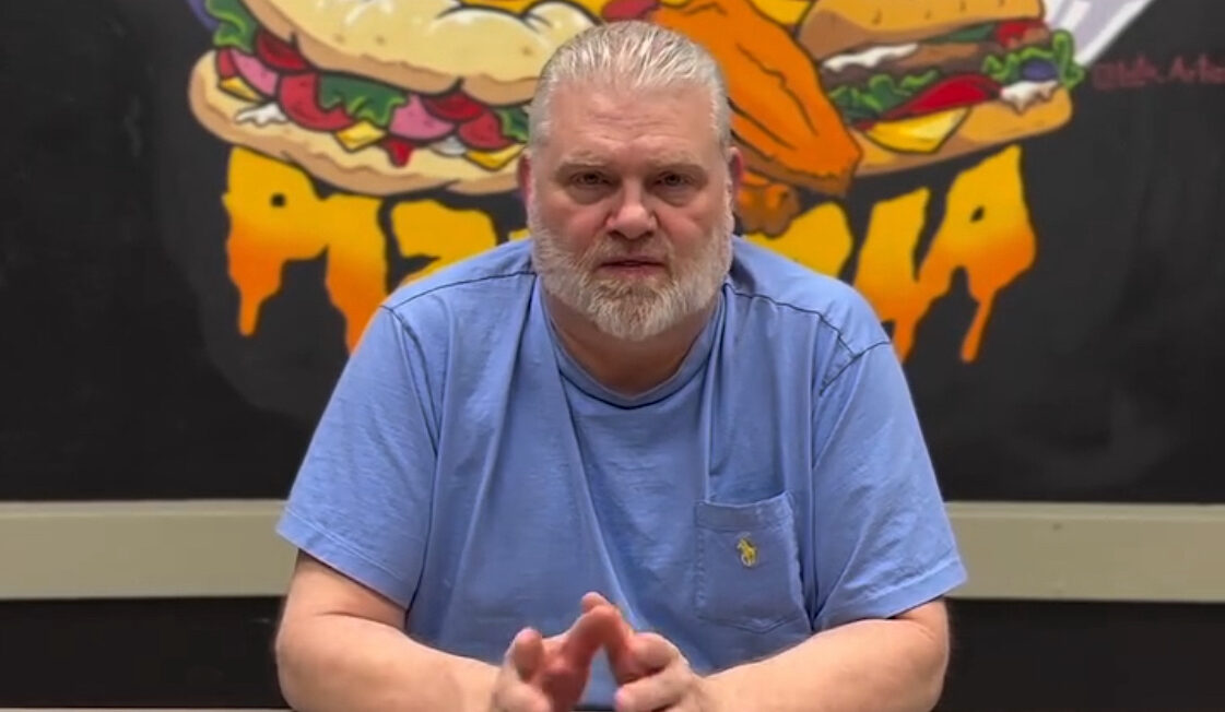 This photo shows Frank Steele, with close-cropped gray hair and wearing a blue shirt, talking to the camera for a video.