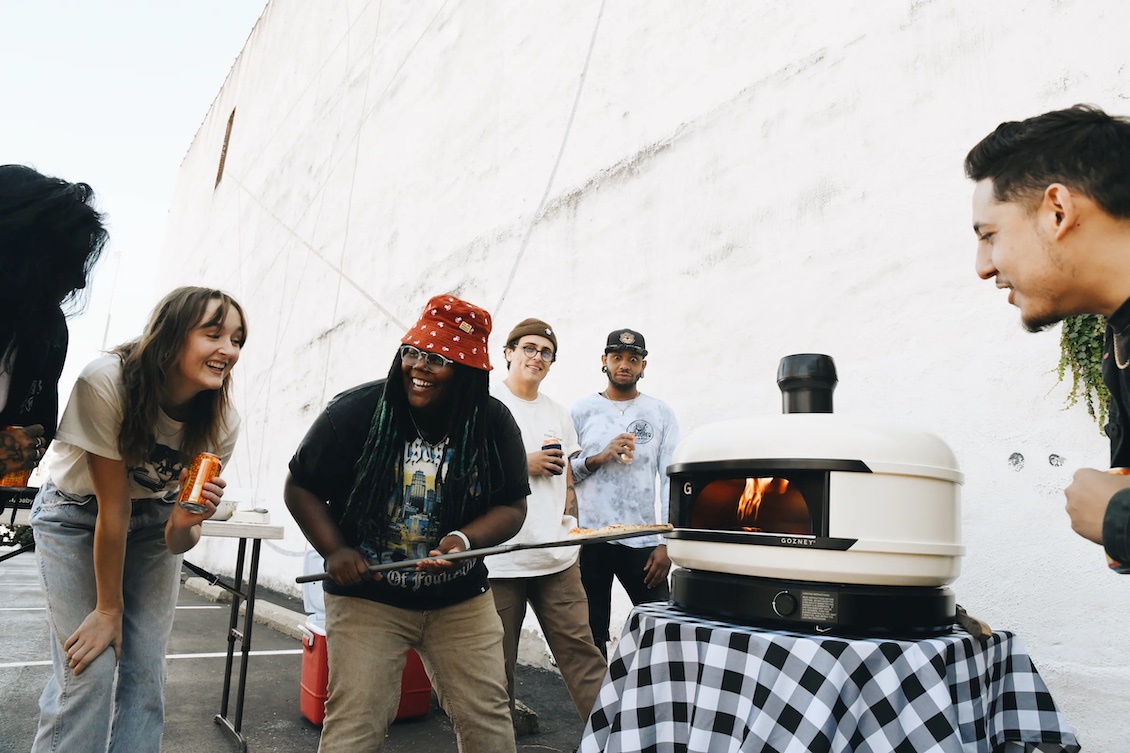This photo shows Jhy Coulter making pizzas for friends with a Gozney portable oven.