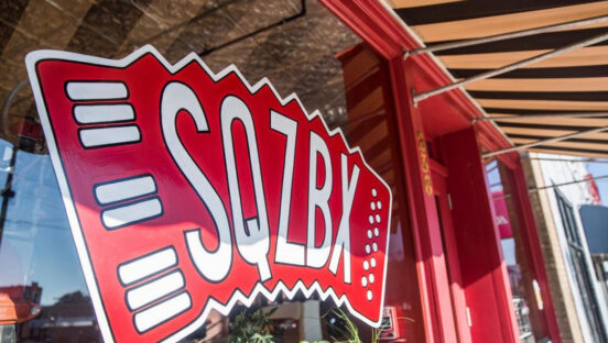 This photo shows the exterior window sign of SZQBX with an accordion-style logo.