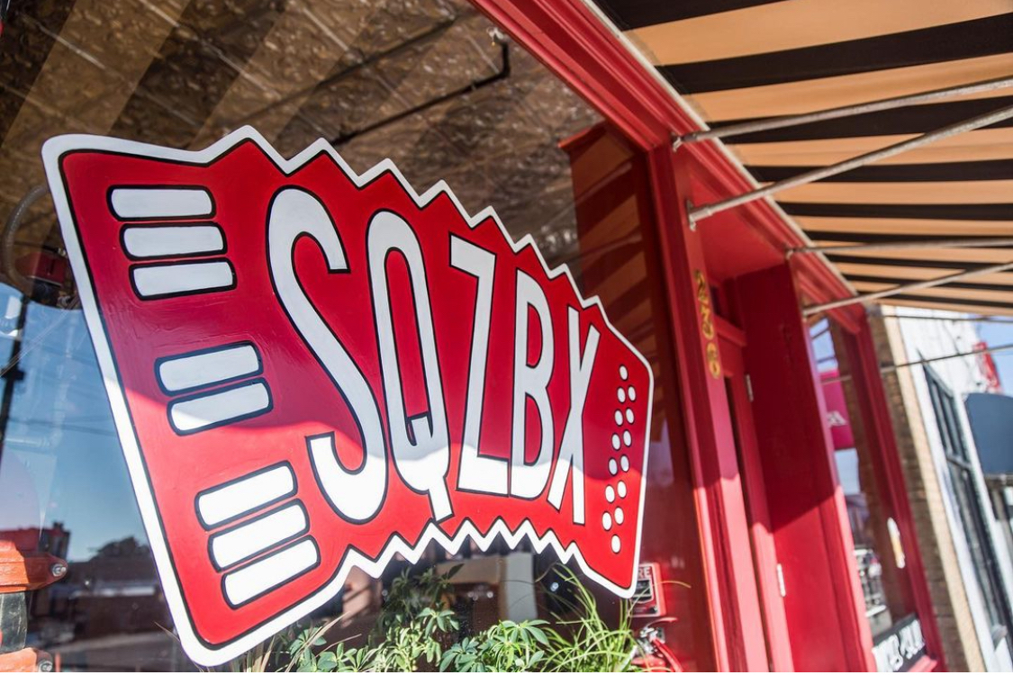This photo shows the exterior window sign of SZQBX with an accordion-style logo.