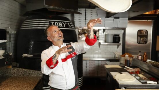 This photo shows Tony Gemignani tossing pizza dough in the kitchen of one of his restaurants.