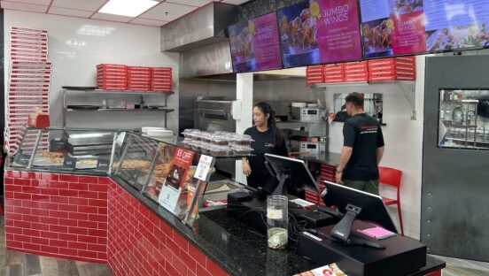This photo shows employees working behind the counter at Cannoli Kitchen Pizza.