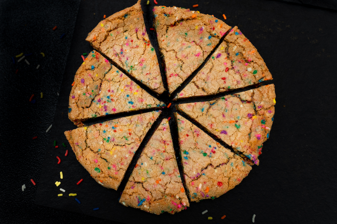 This photo shows an overhead view of the Confetti Cookie cut into pizza-style triangular slices.