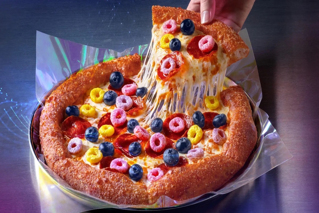 This photo shows a pizza topped with fruit loops cereal and blueberries.