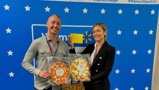 This photo shows Chef Jake Sanderson on the left and Katie Lee on the right. They're both holding a frozen pizza and Katie is displaying her Golden Ticket.