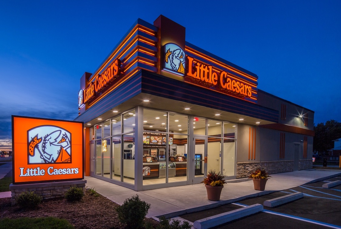This photo shows the exterior of a Little Caesars story, brightly lit, against a dark blue background.