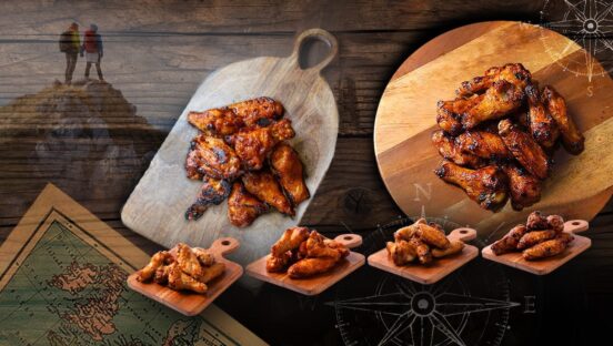 This photo shows a variety of chicken wings set against a background that includes two compasses, two people standing at the top of a mountain and the corner of an old-style map.