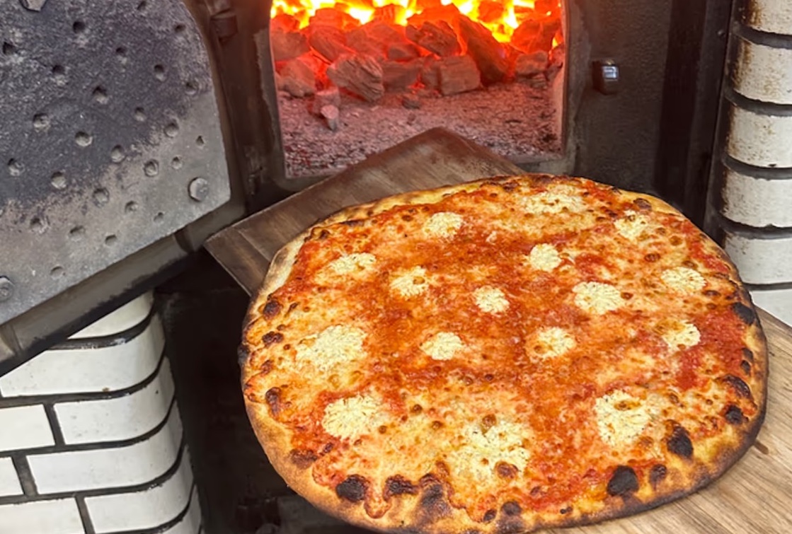 This photo shows the four-cheese Quattro Formaggio pizza perched in front of a blazing coal-oven fire.