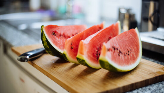 This photo shows four slices of watermelon on a wooden cutting board.
