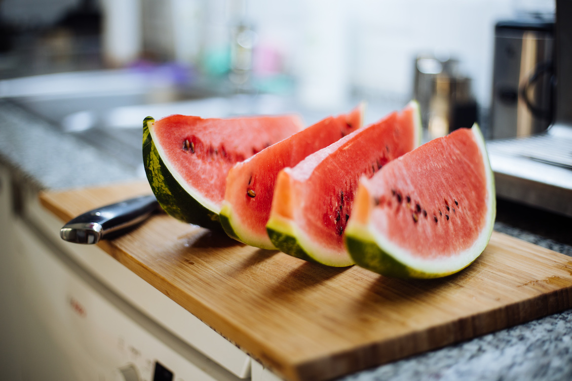 This photo shows four slices of watermelon on a wooden cutting board.