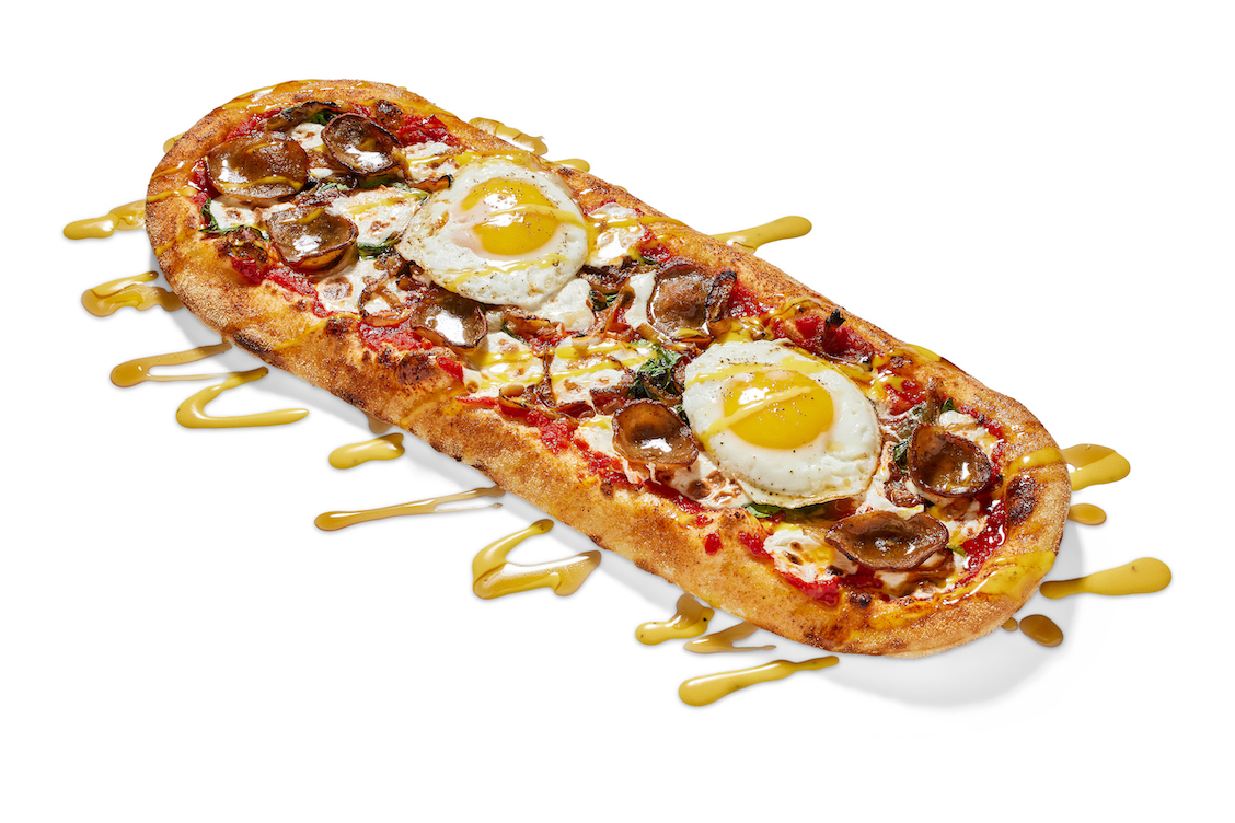This photo shows an oblong-shaped pizza topped with fresh mozzarella, Italian sausage, spinach and grilled onions.