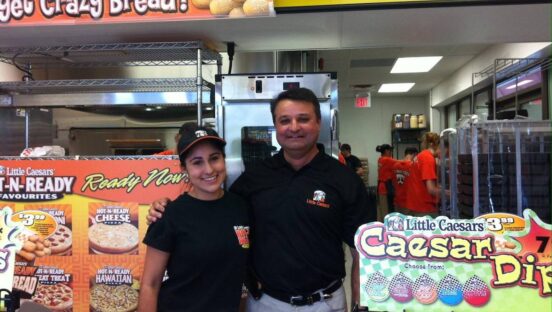 A father-daughter duo pose behind the counter at a Little Caesars store in Barrie, Ontario.