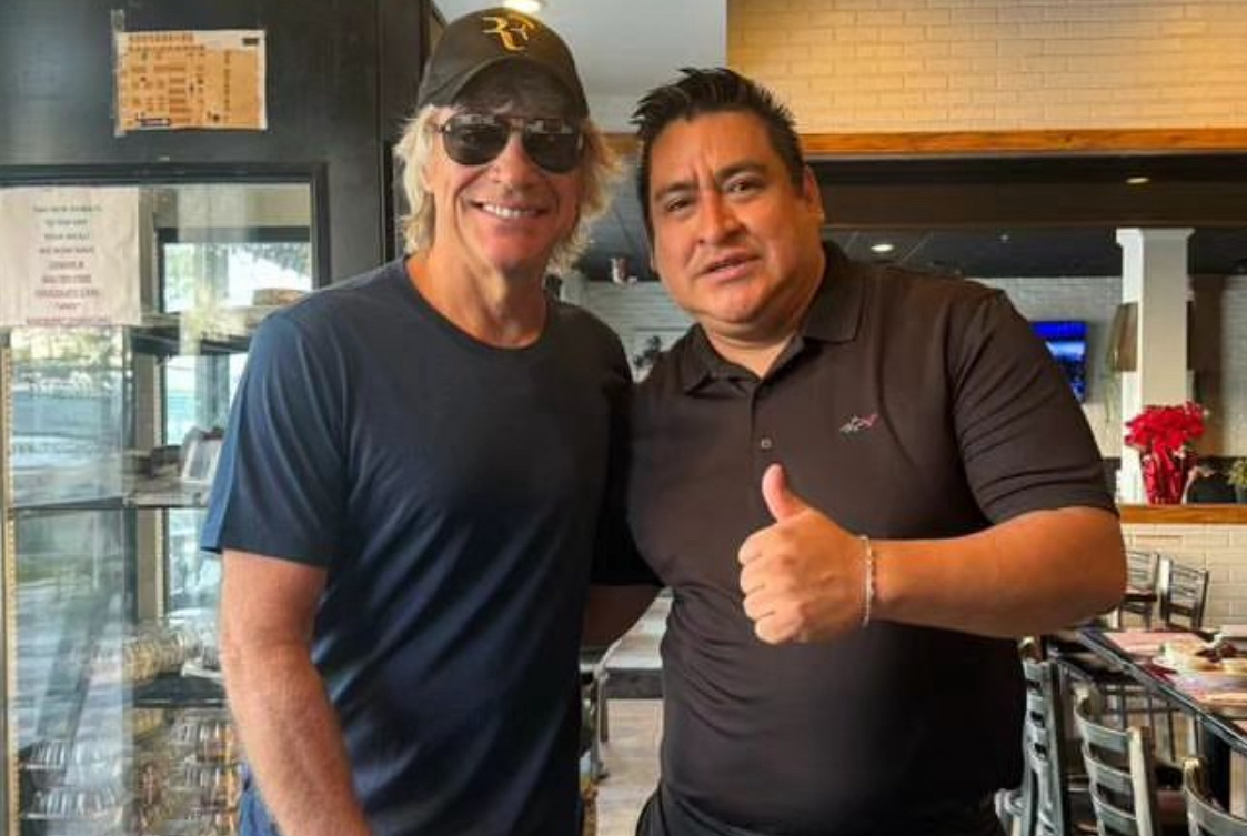 This photo shows Jon Bon Jovi posing with an owner at City Pizza back in December 2023. Bon Jovi is wearing a baseball cap, sunglasses and a dark T-shirt. The owner is wearing a black shirt and giving a thumbs-up.