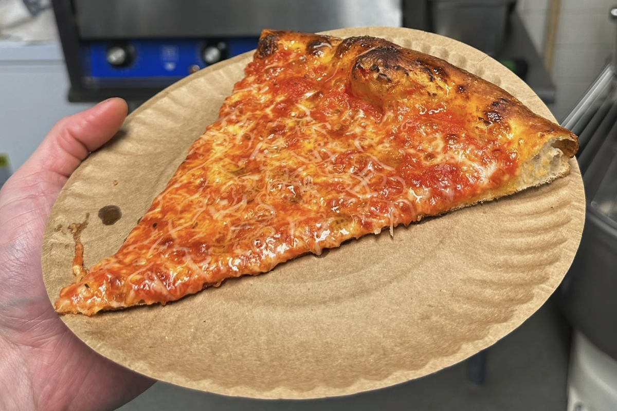 A New York slice of cheese pizza on a paper plate.