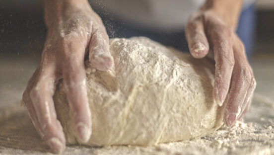 This picture shows a dough ball being shaped by a man's hands.