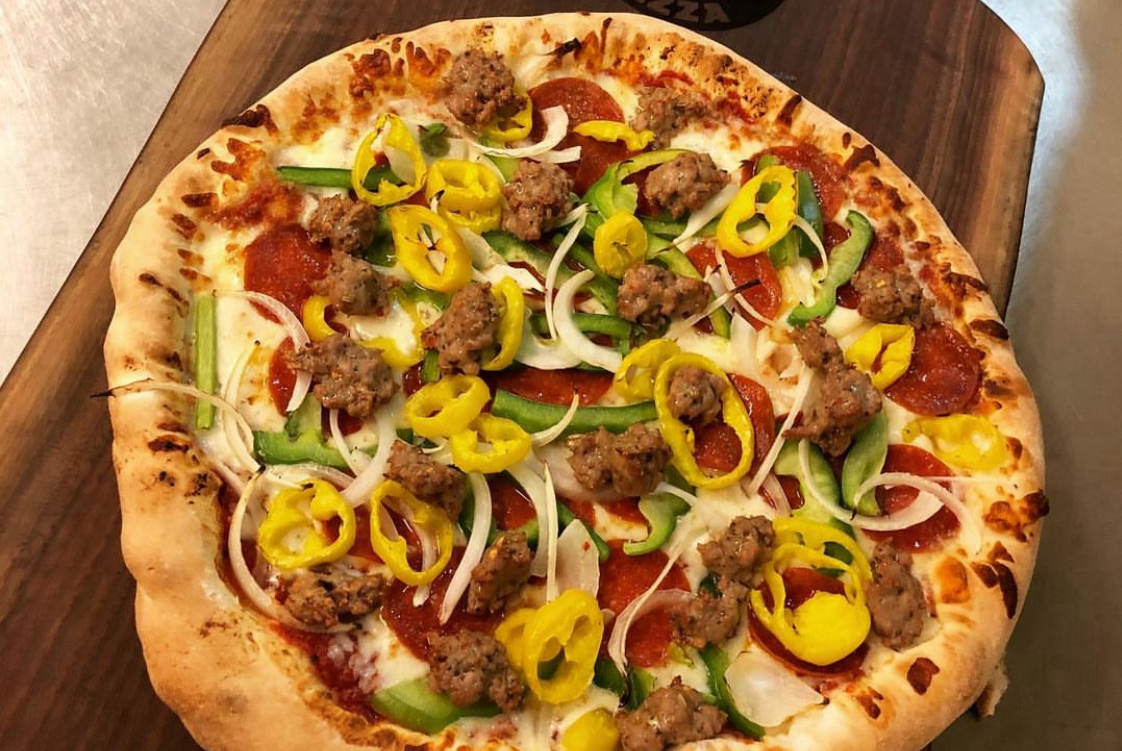 This photo shows a pizza topped with peppers, sausage, and pepperoni.
