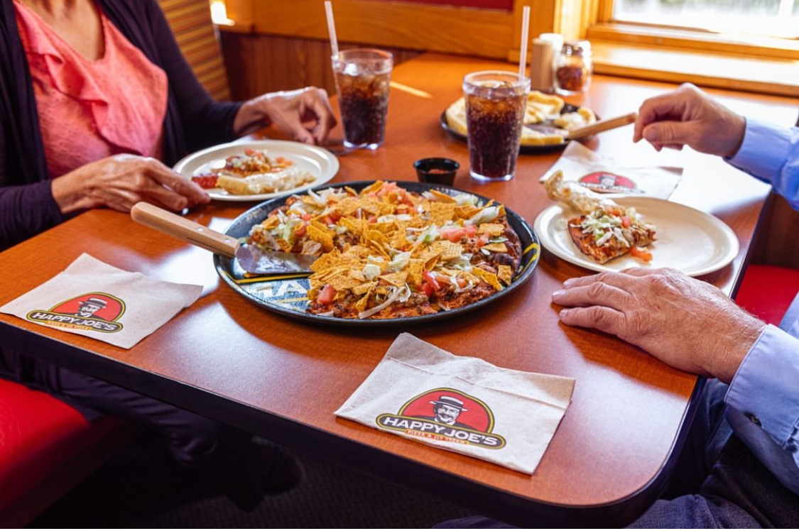 This photo shows a family eating pizza at a Happy Joe's restaurant.