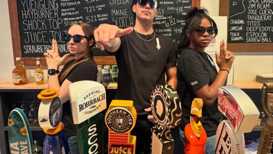 This photo shows three front-of-house team members in a sort of Charlie's Angels pose behind the bar.