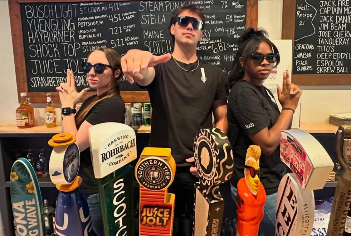 This photo shows three front-of-house team members in a sort of Charlie's Angels pose behind the bar.