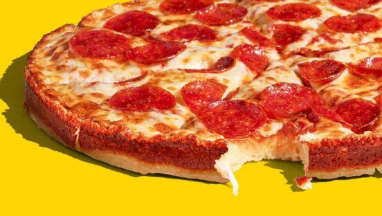 A circular pan pizza on a yellow background.