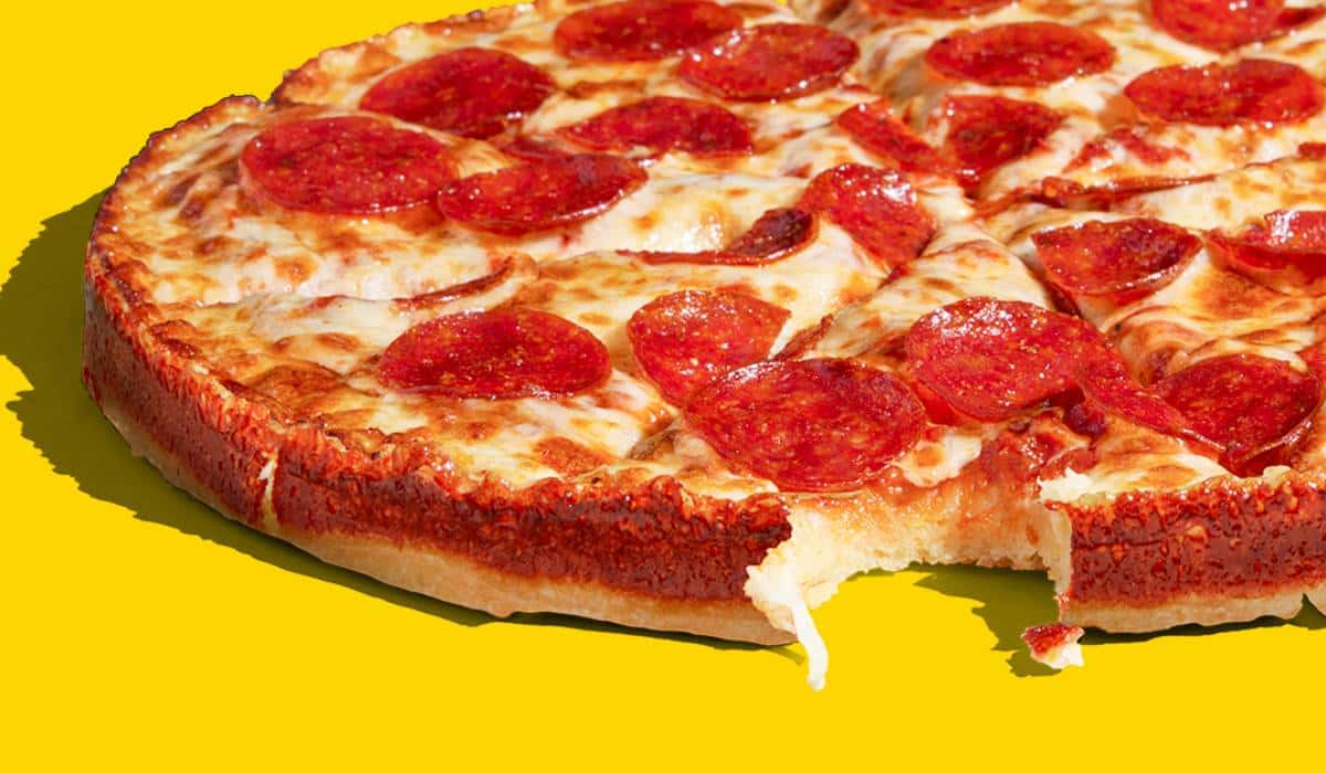 A circular pan pizza on a yellow background.
