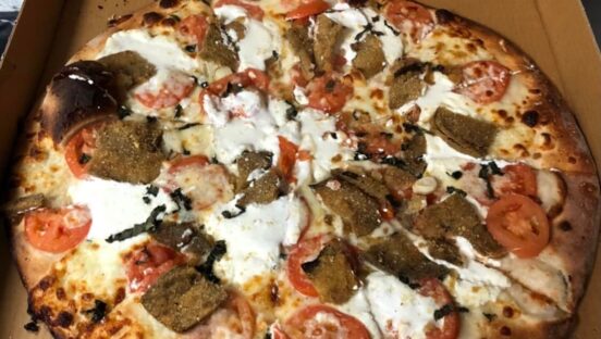This photo shows a Mr. B's pizza topped with tomatoes, ricotta, eggplant and garlic.