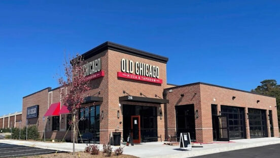This photo shows the exterior of an Old Chicago restaurant against the backdrop of a dark blue sky.