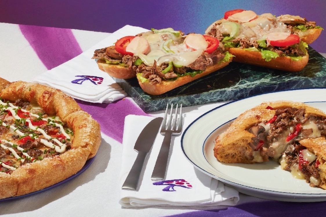 This photo shows a variety of new items from Mellow Mushroom, including a pizza, a calzone and sandwiches.
