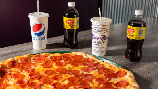 This photo shows a pepperoni pizza with cups of Pepsi and other soft drinks at Manco & Manco Pizza.