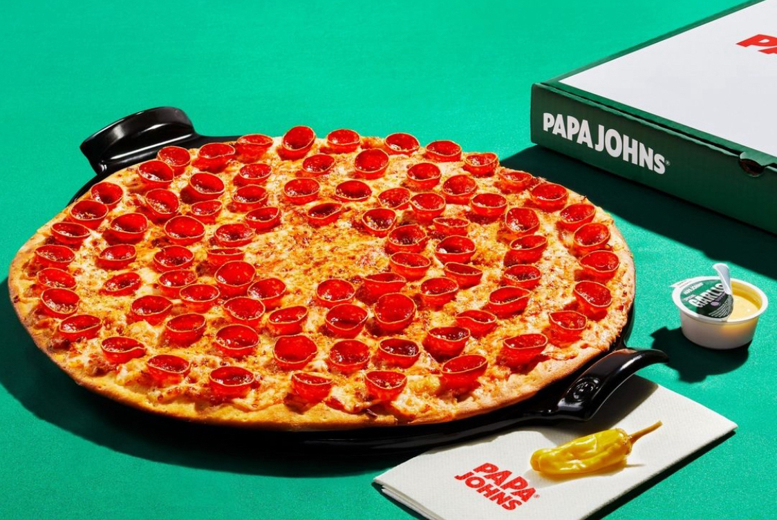 This photo shows a large pizza with cupped pepperoni slices and a Papa Johns pizza box and napkin.