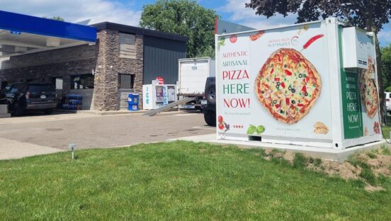 This photo shows a PizzaForno unit situated next to a convenience store.