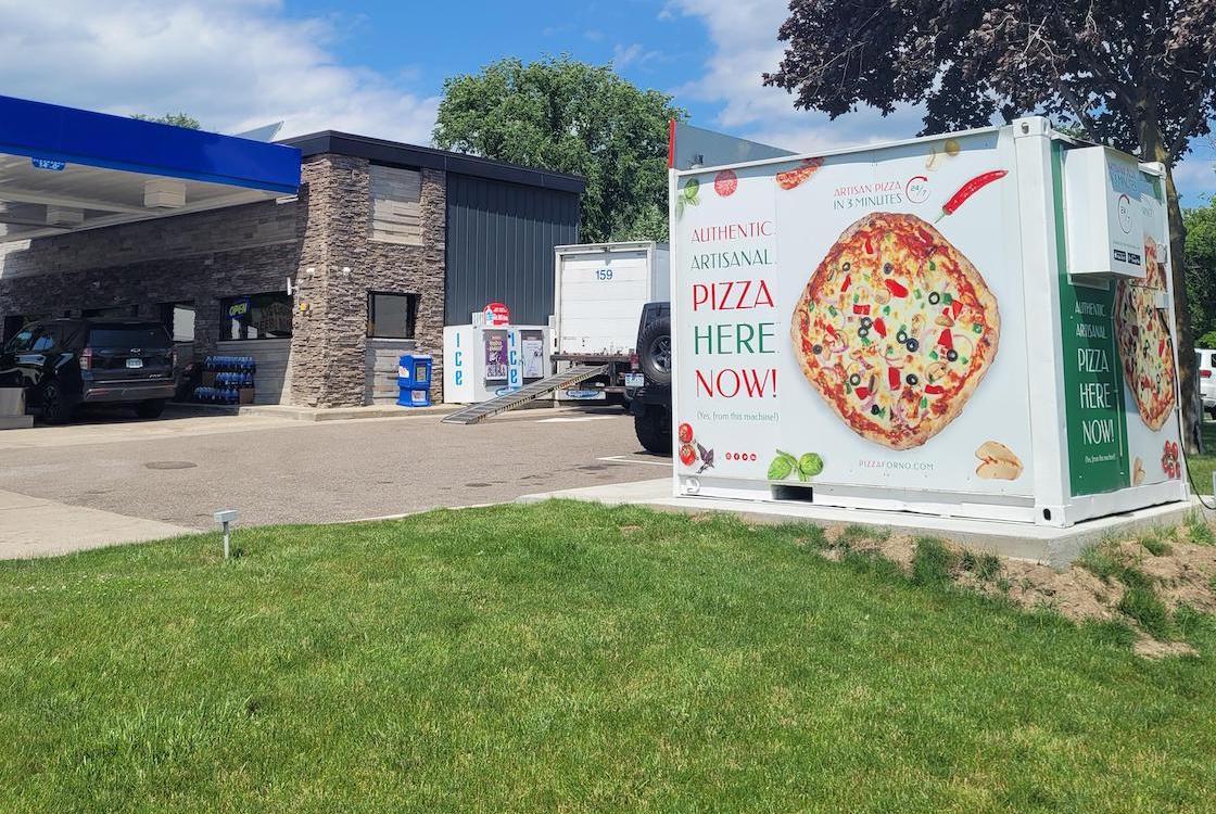 This photo shows a PizzaForno unit situated next to a convenience store.
