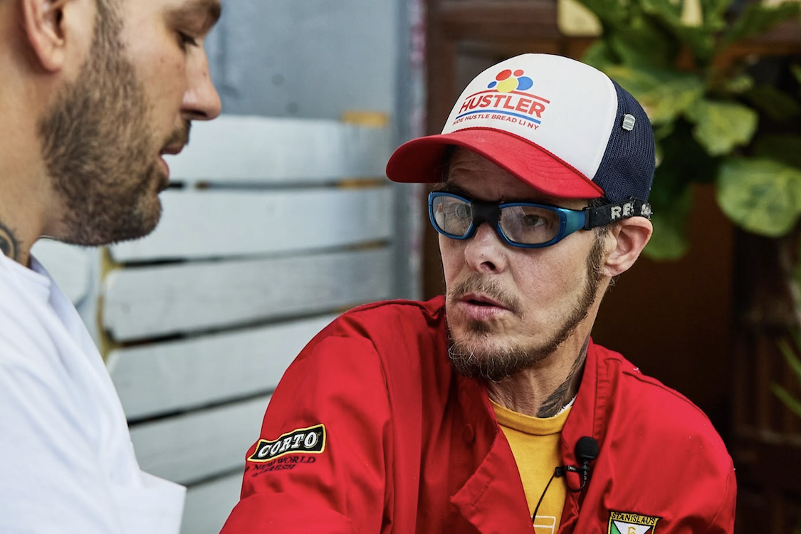 This photo shows Auggie Russo, wearing his trademark glasses, a red chef's jacket and a cap, talking to a customer at a pop-up event.