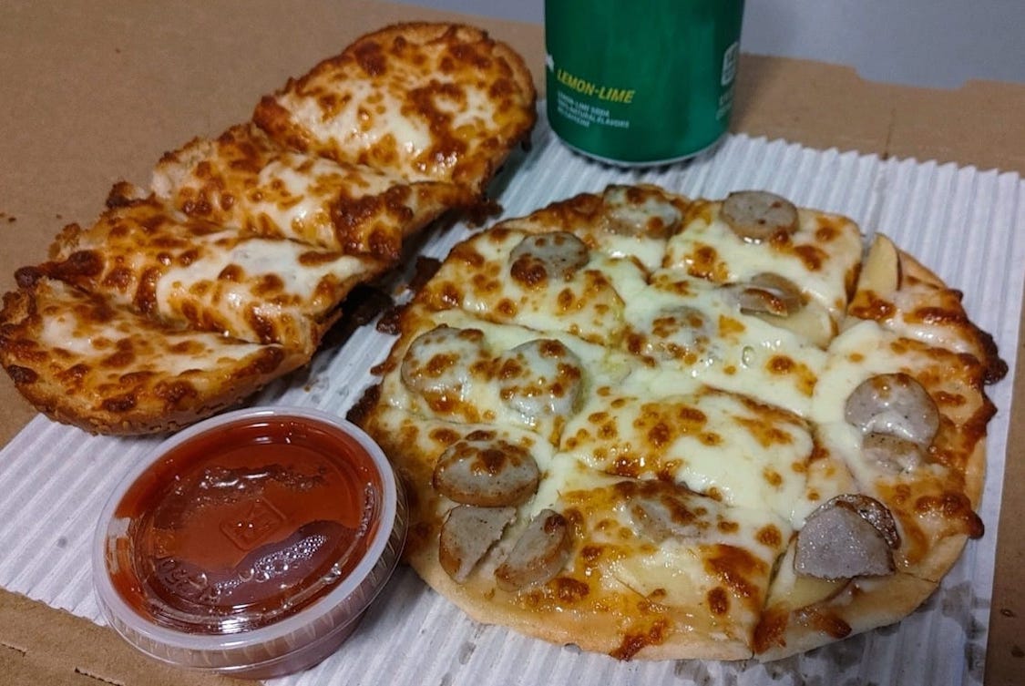 This photo shows the Apples and Bangers pizza recently offered at Tyeger's Pizza Parlor, alongside a flatbread pizza to the left and a cup of dipping sauce.